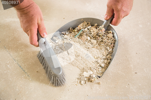 Image of Worker Picking Up Pile of Debris on Cement