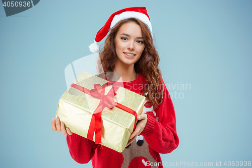 Image of Girl dressed in santa hat with a Christmas gift