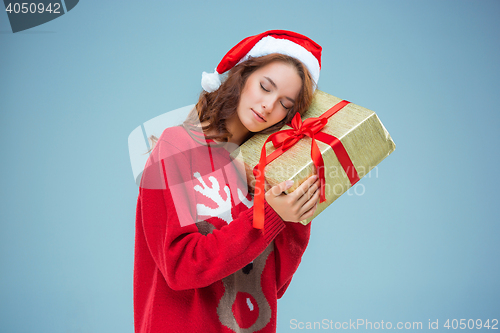 Image of Girl dressed in santa hat with a Christmas gift