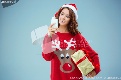 Image of Girl dressed in santa hat with a Christmas gift and phone