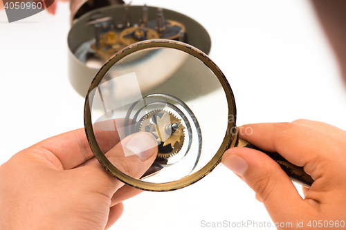 Image of The male hand with magnifier and clockwork