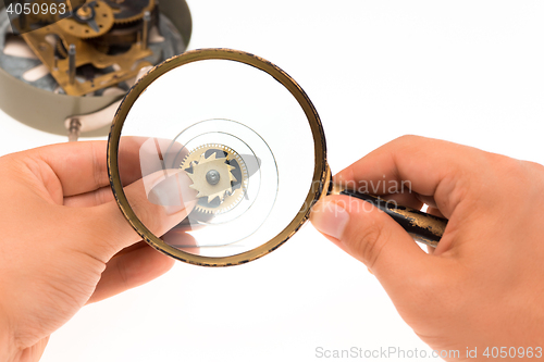 Image of The male hand with magnifier and clockwork