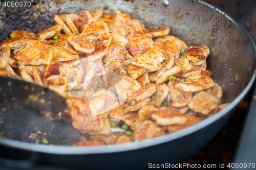 Image of close up of meat in wok pan at street market