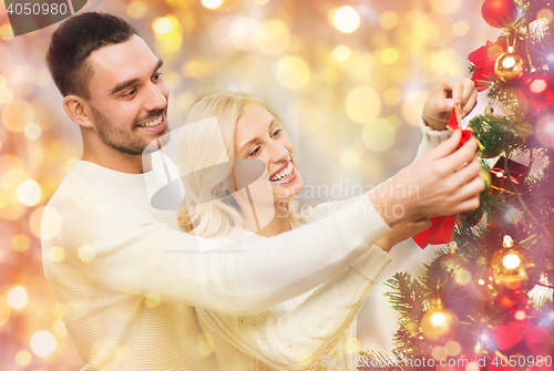 Image of happy couple decorating christmas tree at home