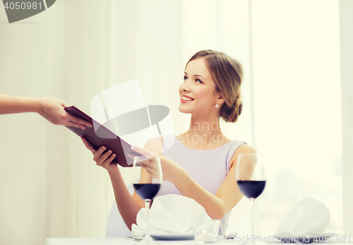 Image of smiling woman giving menu to waiter at restaurant