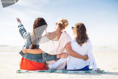 Image of group of young women hugging on beach