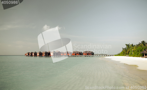 Image of bungalow huts in sea water on exotic resort beach