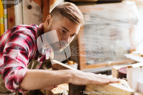 Image of carpenter working with wood plank at workshop