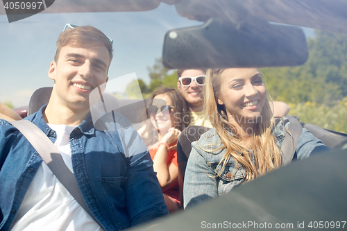 Image of happy friends driving in cabriolet car