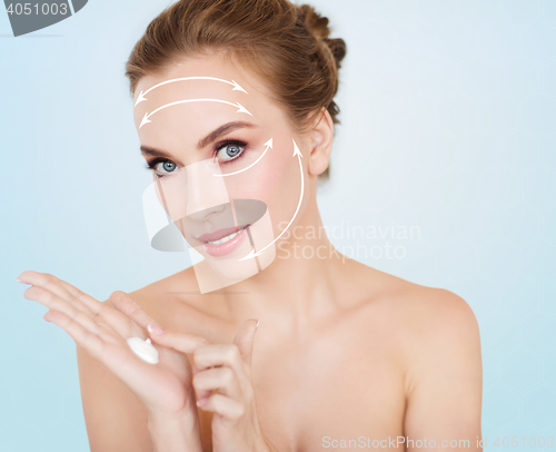 Image of happy young woman with moisturizing cream on hand