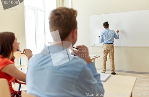 Image of students and teacher writing on school white board