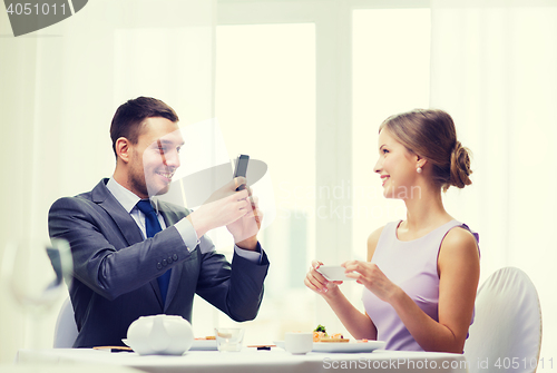 Image of smiling couple with sushi and smartphones