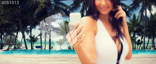 Image of young woman taking selfie with smartphone on beach