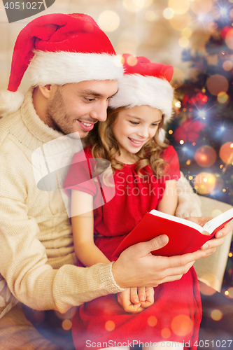 Image of smiling father and daughter reading book