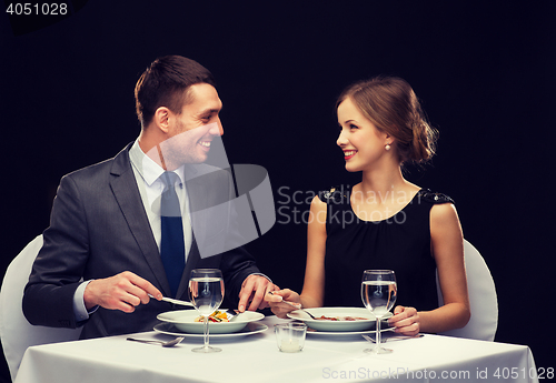 Image of smiling couple eating main course at restaurant