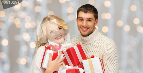 Image of happy couple in sweaters holding christmas gifts