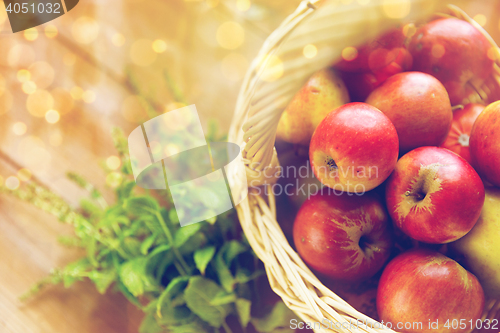 Image of close up of basket with apples and herbs on table