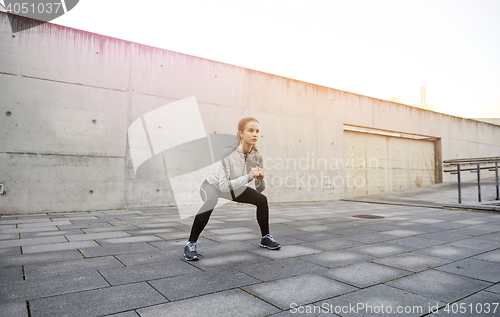 Image of happy woman doing squats and exercising outdoors