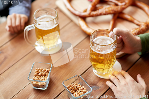 Image of close up of hands with beer mugs at bar or pub