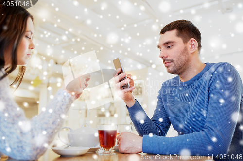Image of couple with smartphones drinking tea at cafe
