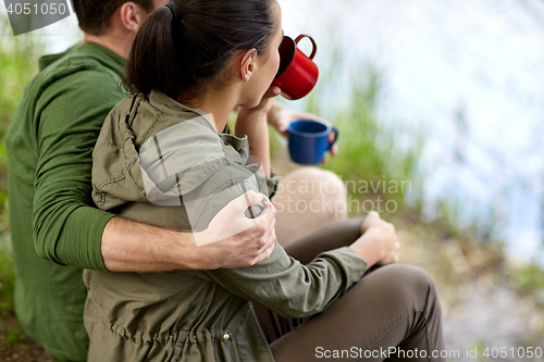 Image of happy couple with cups drinking in nature