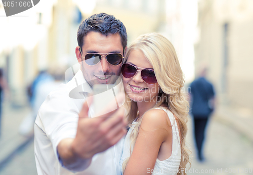 Image of smiling couple with smartphone in the city