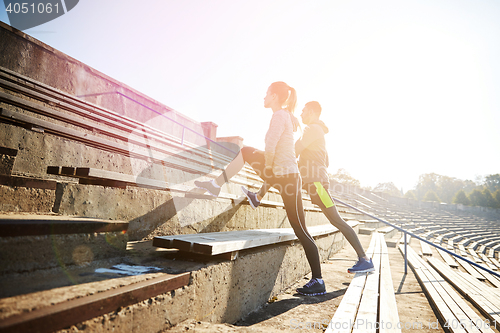 Image of couple stretching leg on stands of stadium