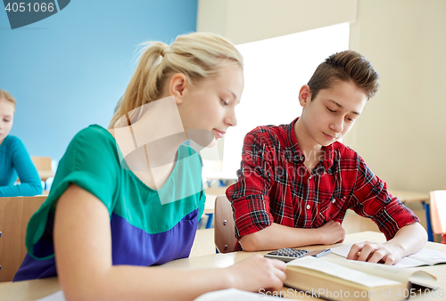 Image of students with book and calculator at school lesson