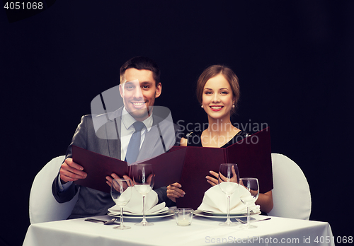 Image of smiling couple with menus at restaurant