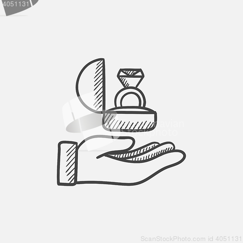 Image of Hand holding gift box with ring sketch icon.