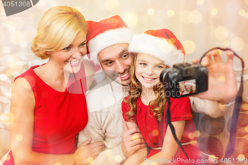 Image of smiling family in santa helper hats taking picture