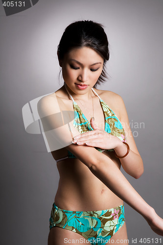 Image of Asian woman applying lotion