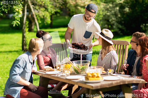 Image of happy friends having dinner at summer garden party