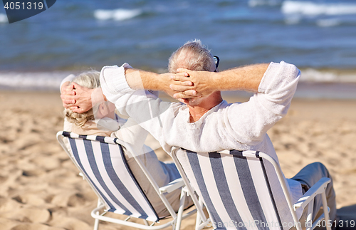 Image of senior couple sitting on chairs at summer beach