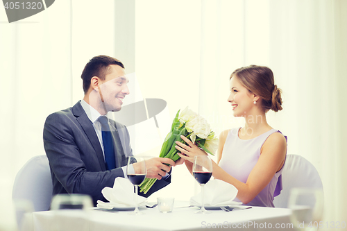 Image of smiling man giving flower bouquet at restaurant