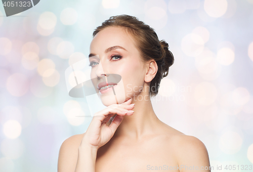 Image of beautiful young woman touching her face