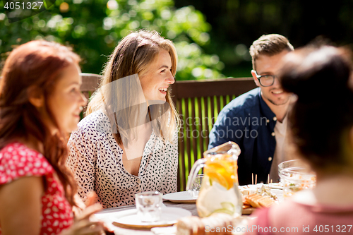 Image of happy friends having dinner at summer garden party