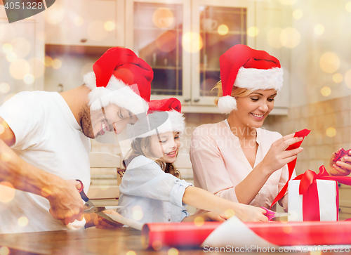 Image of smiling family in santa helper hats with gift box