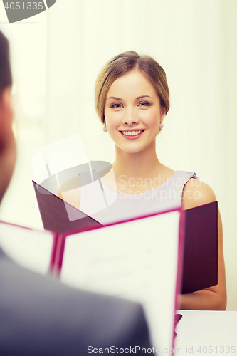 Image of smiling young woman with menu at restaurant