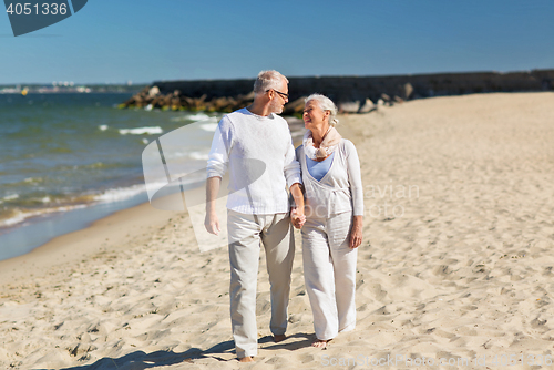 Image of happy senior couple holding hands on summer beach