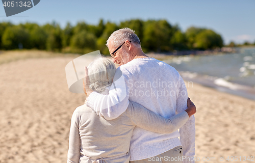 Image of happy senior couple hugging on summer beach