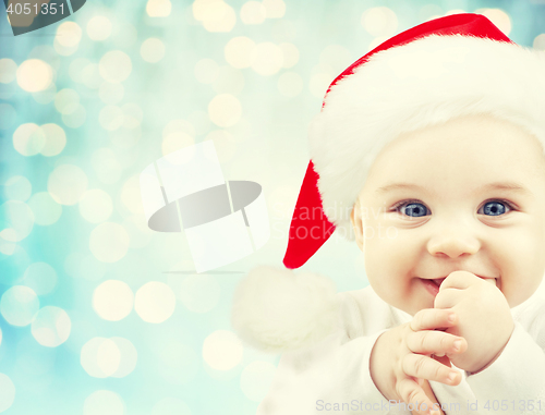 Image of happy baby in santa hat over blue holidays lights