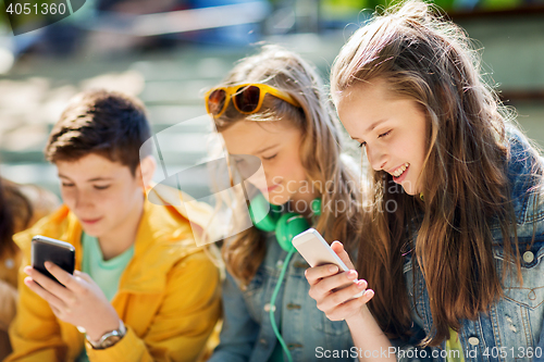 Image of happy teenage friends with smartphones outdoors