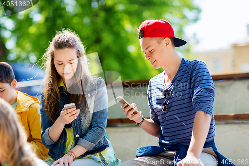 Image of happy teenage friends with smartphones outdoors