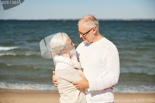 Image of happy senior couple hugging on summer beach
