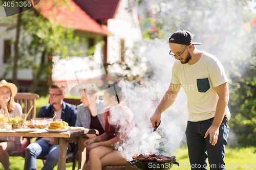 Image of man cooking meat on barbecue grill at summer party