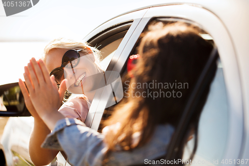 Image of happy teenage girls or women in car at seaside