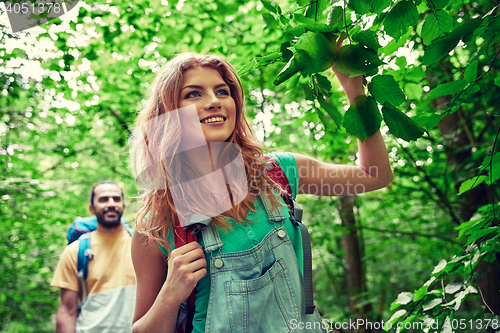 Image of happy couple with backpacks hiking in woods