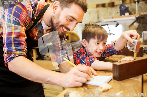 Image of dad and son with ruler measuring plank at workshop