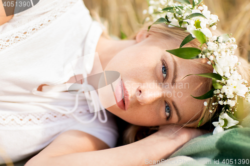 Image of happy woman in wreath of flowers on cereal field